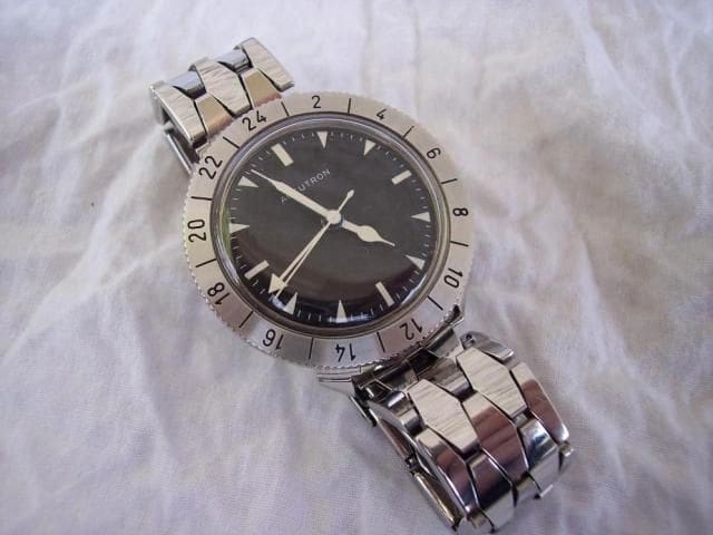 Silver wristwatch with black face and numbers.