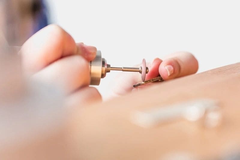 Person using a rotary tool on jewelry.