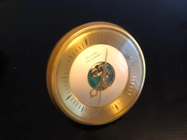 A gold clock with a white face and a black background