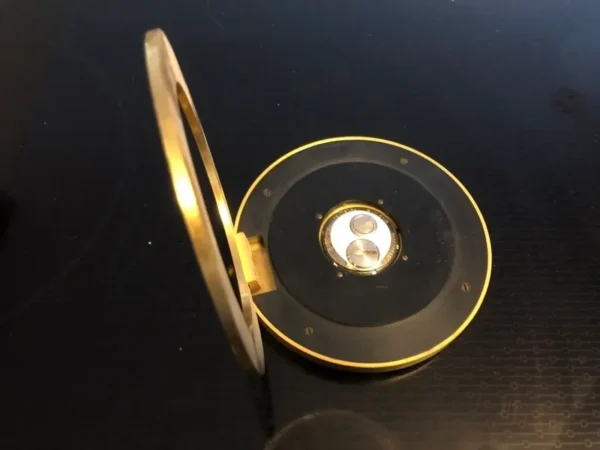 A black and gold compact mirror on top of a table.