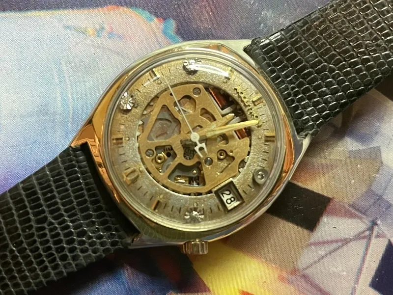 A watch with a gold face and black strap.