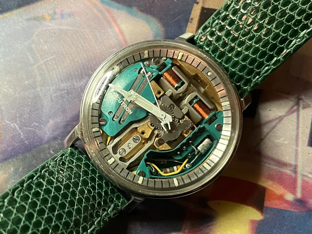 A watch with some parts missing on top of a map.