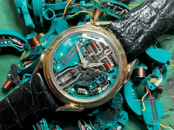 A watch is sitting on top of some green wires.