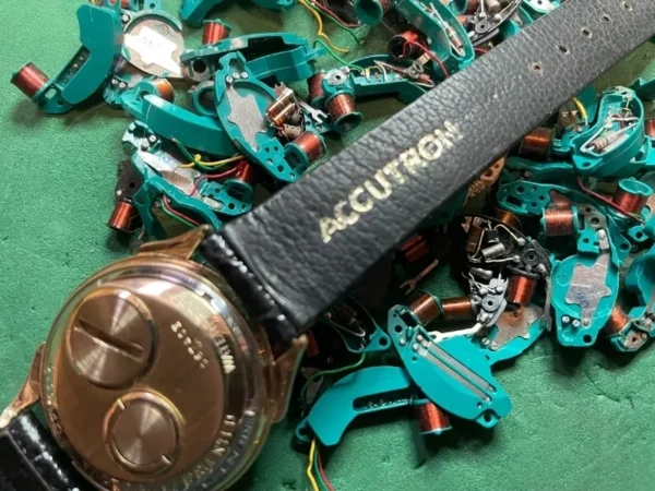 A watch laying on top of some electronic components.