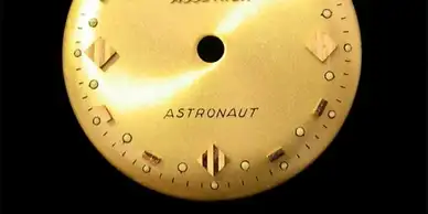 A close up of the astronaut logo on an analog watch