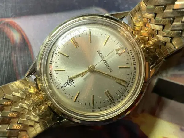 A gold watch with roman numerals on it.