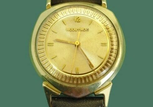 Gold Accutron wristwatch with brown leather band.