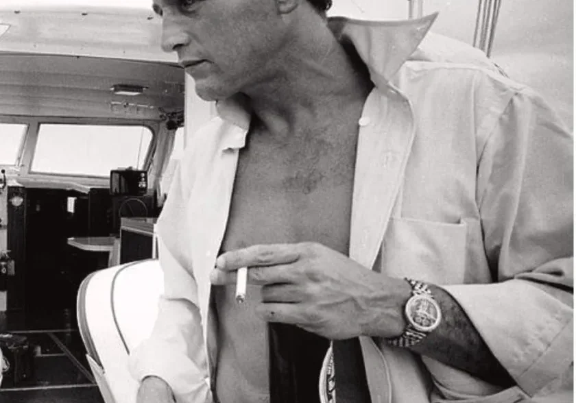 Man in white shirt, smoking on a boat.