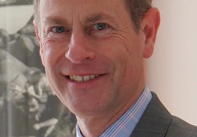 Smiling man in suit with pink tie.