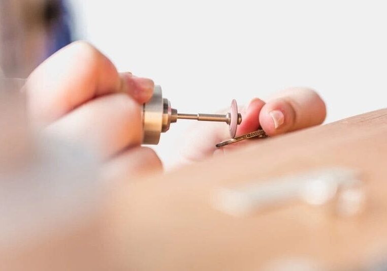 Person using a rotary tool on jewelry.